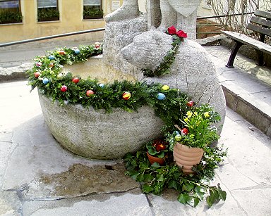 Osterbrunnen Egloffstein: Festlich geschmückter "trinkender" Bär zu Füßen von Egilulf